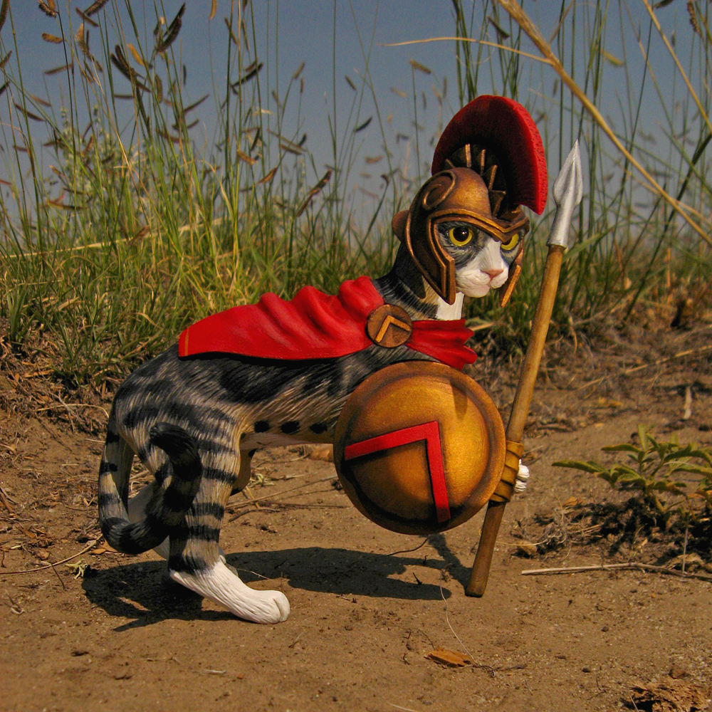 A polymer clay sculpture of a warrior Spartan kitty. King Leonidas, to be exact. This collectible OOAK cat figurine has a spear in one paw, and a Spartan shield in his other. The tabby wears a magnificent red half-cape. He looks determined, like he is about to deflect an incoming enemy blow.